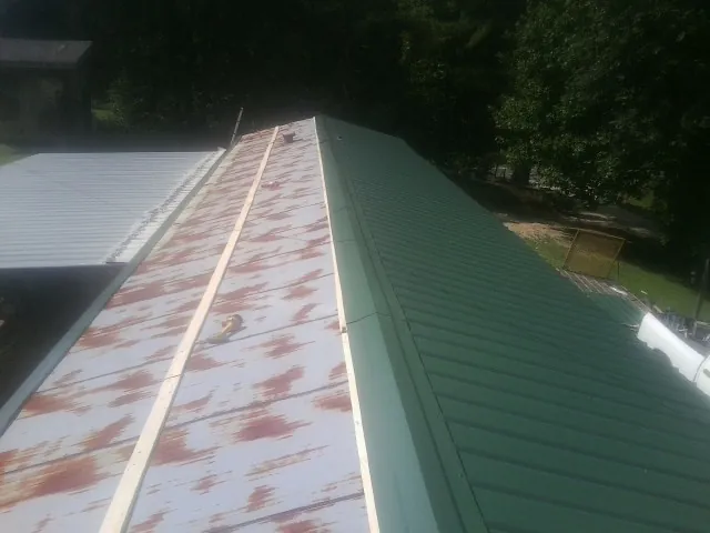 Old rusted panels beside newly installed green metal roofing — Wind Damage Roof Repair by Roofing Brothers in Marshfield