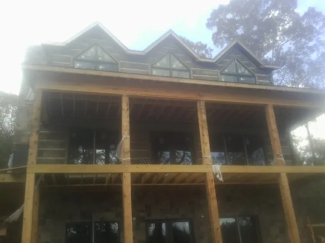 Dormers and porch framing on a large log home under construction — Roof Coating work by our crew in Marshfield